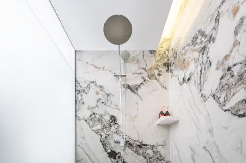 a shower in a bathroom with a marble wall at Wahid Prime Hotel Salatiga in Salatiga