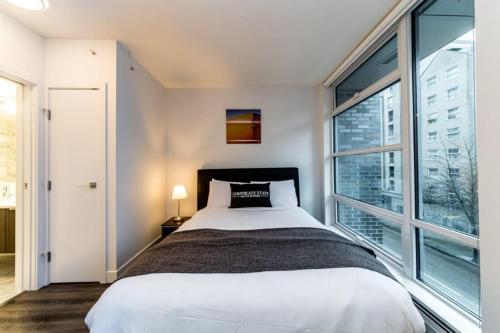 ein Schlafzimmer mit einem Bett und einem großen Fenster in der Unterkunft Corporate Stays Tate 1 Bedroom in Vancouver