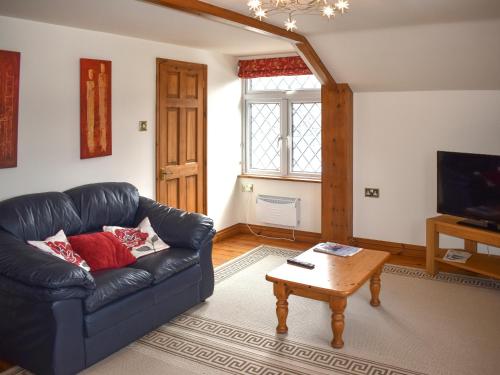 a living room with a black leather couch and a coffee table at Orchardlea Apartment in Coldridge