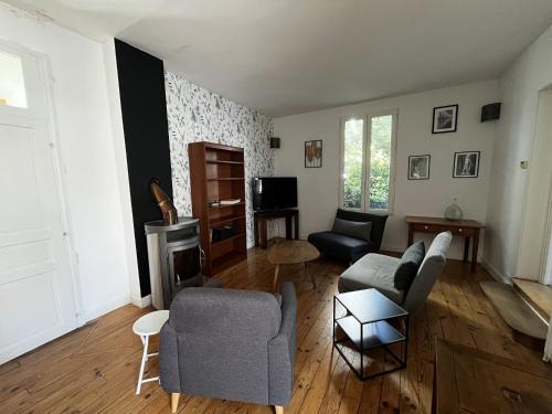 ein Wohnzimmer mit Sofa, Sesseln und Fernseher in der Unterkunft L Atypique Briviste - Villa Montyon in Brive-la-Gaillarde