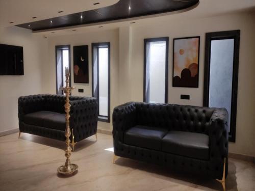a living room with two black couches and a television at Sivashree Residency in Tiruvannāmalai