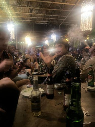 a group of people sitting at a table with bottles of alcohol at The Peace Hostel in Arambol