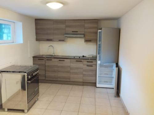une cuisine avec des armoires en bois et un réfrigérateur en acier inoxydable dans l'établissement Appartement T4 rez jardin Avec grand space vert, à Livry-Gargan
