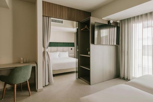 a bedroom with a bed and a desk with a chair at Regional Hotel by NEU Collective in Il-Gżira
