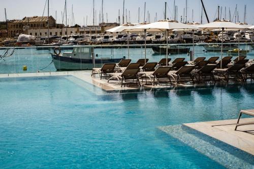 a swimming pool with lounge chairs in a marina at Strand Suites by NEU Collective in Il-Gżira