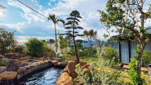 a backyard with a pond with rocks and trees at Homestay Đồi Mây Lộc Tân Bảo Lộc in Bảo Lâm