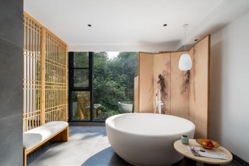 Un baño con bañera y una gran ventana. en Guilin Lakeview Boutique Lodge, en Guilin