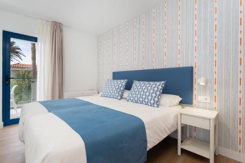 ein Schlafzimmer mit einem blau-weißen Bett und einem Fenster in der Unterkunft Alsol Los Caribes 1 in Playa del Ingles