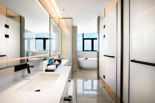 a bathroom with a tub and a sink and mirror at Latsavong Wanda Vista Vientiane in Vientiane