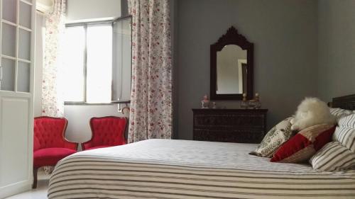 a bedroom with a bed with a mirror and red chairs at TRIANA HOME & Free Parking in Seville