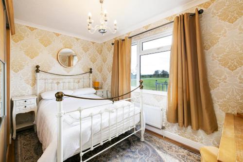 Un dormitorio con una cama blanca y una ventana. en Immaculate 3-Bedroom Private Lodge near York, en York