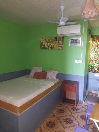 a bedroom with a bed with a green wall at baobolong guesthouse in Koli Kunda