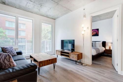 un salon avec un canapé, une télévision et un lit dans l'établissement Corporate Stays Le Shaughn 1 Bedroom, à Montréal