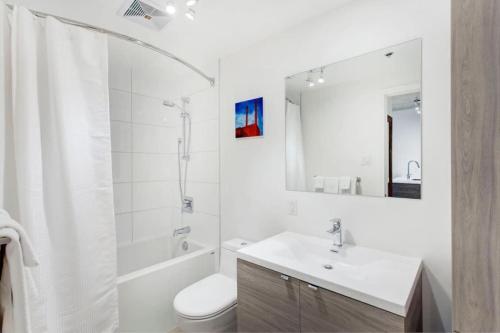 une salle de bain avec un lavabo, des toilettes et un miroir dans l'établissement Corporate Stays Le Shaughn 1 Bedroom, à Montréal