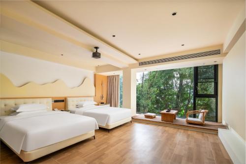 Un dormitorio con dos camas y una gran ventana. en Guilin Lakeview Boutique Lodge, en Guilin