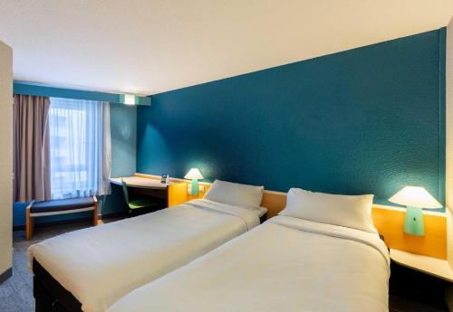 a hotel room with two beds and a desk at B&B HOTEL Orléans Centre Foch in Orléans