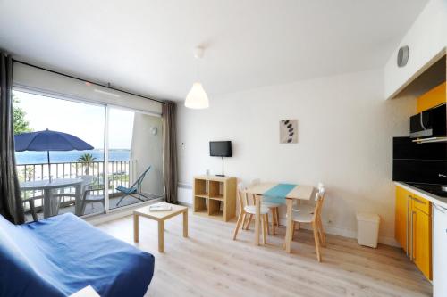 a living room with a table and a kitchen with a balcony at Résidence de Tourisme l'Albatros in Palavas-les-Flots