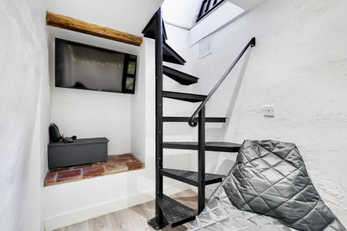 a black spiral staircase in a white room with a tv at 1 Crarves in Docking