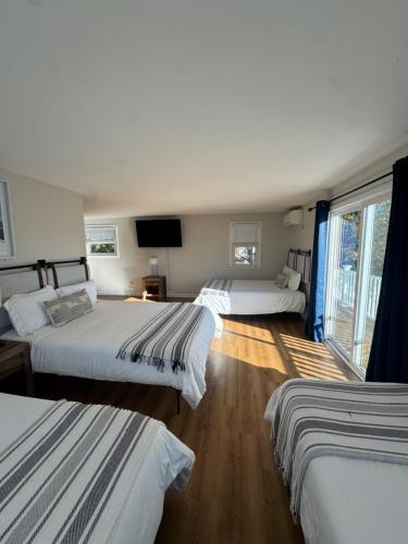 een hotelkamer met drie bedden en een flatscreen-tv bij Waterfront Escape Hottub, Pets Ok, Pool Table in Dennis