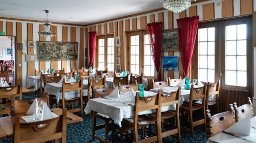 un comedor con mesas, sillas y cortinas rojas en Tallhöjden hotel & Nature Lodge, en Simlångsdalen