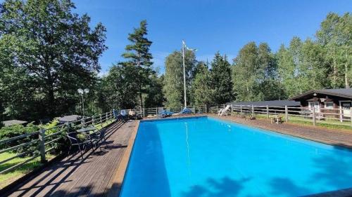 a large blue swimming pool with a wooden deck at Tallhöjden hotel & Restaurant in Simlångsdalen