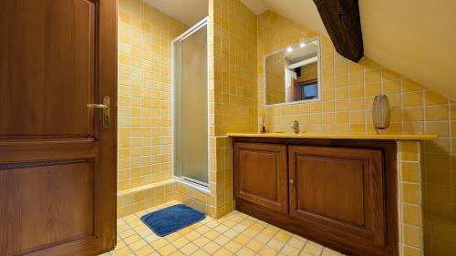 ein gelb gefliestes Badezimmer mit Waschbecken und Dusche in der Unterkunft Les Perles du Ried - Gîte 202 in Boofzheim