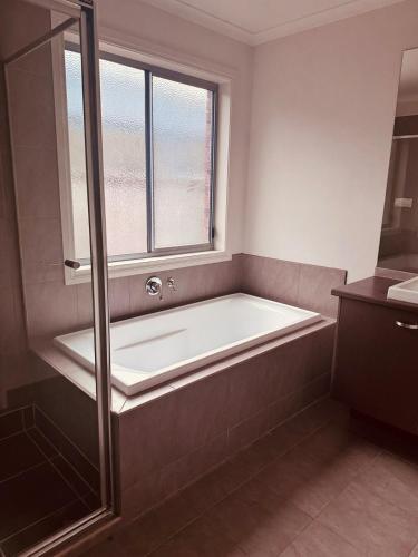 a bath tub in a bathroom with a window at 4 bedroom house in Berwick springs in Narre Warren South