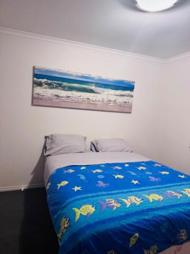 a bedroom with a bed with a blue blanket at 4 bedroom house in Berwick springs in Narre Warren South