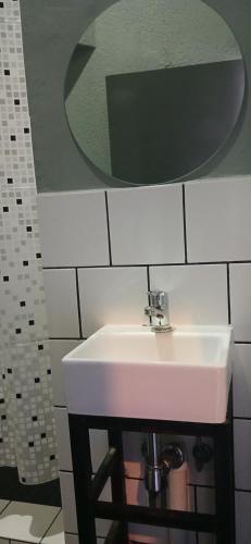 a white sink in a bathroom with a mirror at Stylish Bachelor with Oak Floors & View in Johannesburg