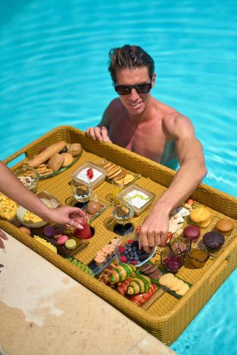 帕利乌里翁美瑞格Spa度假村的一个男人坐在水中，桌上摆着食物。