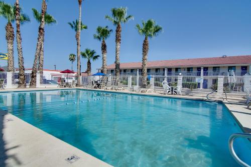 a large swimming pool with palm trees in front of a building at Motel 6 Eloy Arizona Casa Grande in Eloy