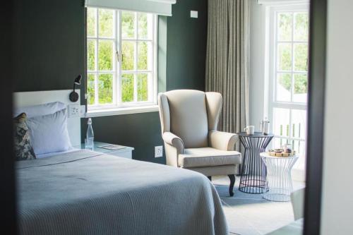 a bedroom with a bed and a chair and window at Vida Nova Retreat in Hout Bay