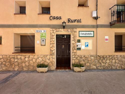 una fachada de un edificio con una puerta marrón en Entrefrutales, en La Vilueña