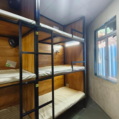a room with three bunk beds with a window at Hans Dormitory in Mumbai