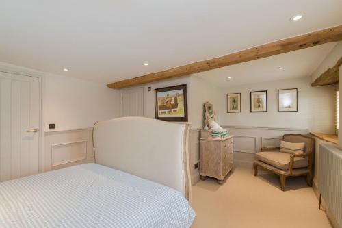 ein Schlafzimmer mit einem weißen Bett und einem Stuhl in der Unterkunft Cotswold Cottage- Central Witney in Witney