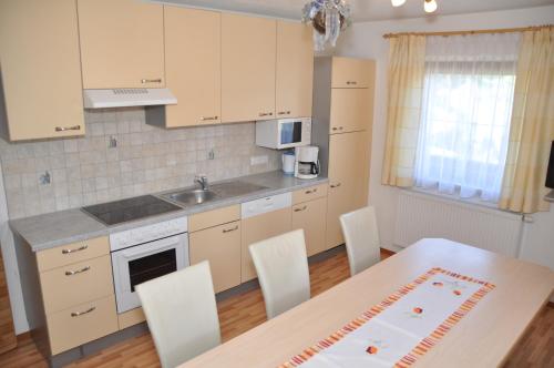 uma cozinha com uma mesa e cadeiras e um lavatório em Flörl em Zell am Ziller