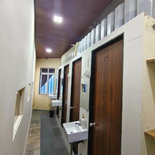 a bathroom with two sinks and a wooden door at Hans Dormitory in Mumbai