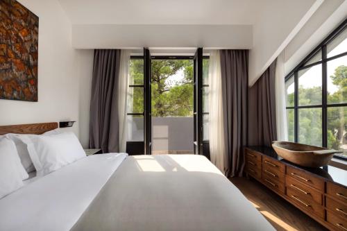 a bedroom with a large bed and a large window at Centrale Lustica Bay by Angsana in Radovići