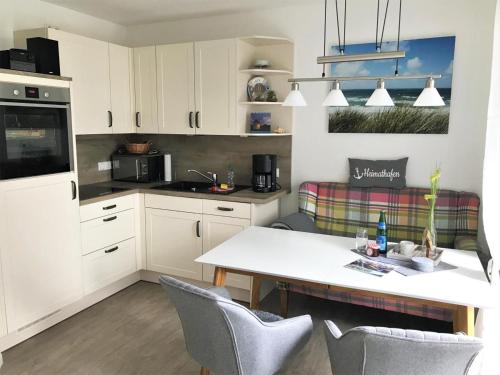 クックスハーフェンにあるMarina Pier 96の白いキャビネットとテーブルと椅子のあるキッチン