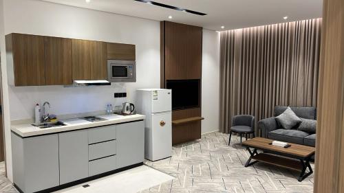 a kitchen with a refrigerator and a chair and a table at اجنحة دانة DANAT Suites الرياض حي اليرموك in Riyadh