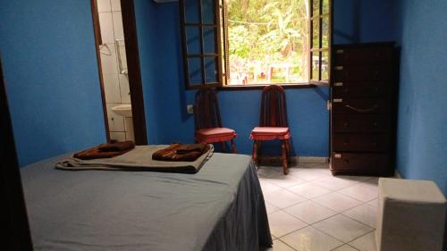 a bedroom with a bed and two chairs and a window at SacodoCeu2026 in Angra dos Reis