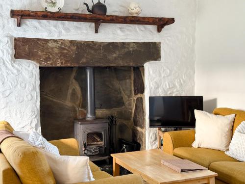 a living room with a fireplace with two couches and a tv at Yellow Cottage, Doolin in Knockfin Cross Roads