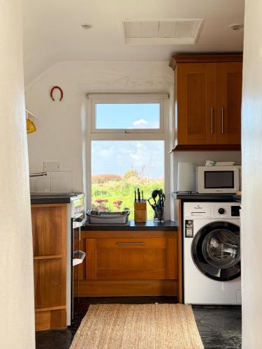 a kitchen with a washing machine and a window at Yellow Cottage, Doolin in Knockfin Cross Roads