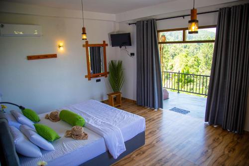 a bedroom with a bed with pillows and a balcony at Tunnel Top Inn Ella in Ella