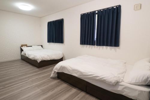 two beds in a room with blue curtains at FabulousOdawara in Odawara
