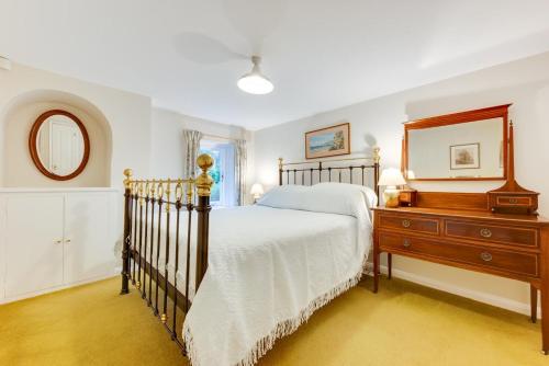 a bedroom with a bed and a dresser and a mirror at Garden Flat in Sandwich