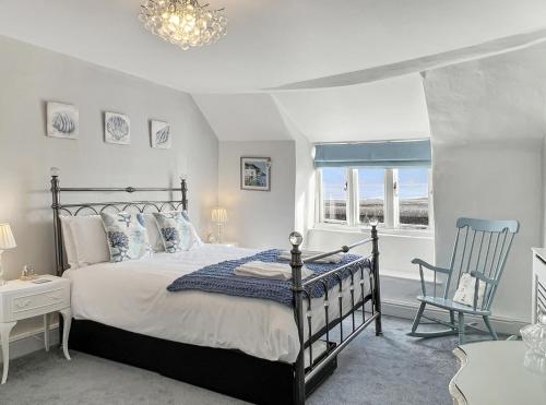 a bedroom with a bed and a chair and a window at Captains Cottage Minehead in Minehead