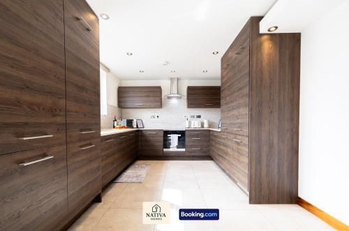 a kitchen with wooden cabinets and a hallway at Spacious 2BR, 2BA Apt By Nativa Homes Short Lets & Serviced Accommodation Harrow With Fast WiFi, Kitchen in Harrow