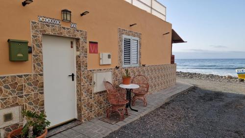 ein Gebäude mit einem Tisch und Stühlen am Meer in der Unterkunft Casa Carmen in Castillo del Romeral