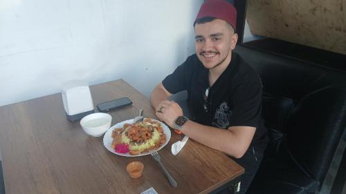 a man sitting at a table with a plate of food at River BPR Hostel in Tbilisi City